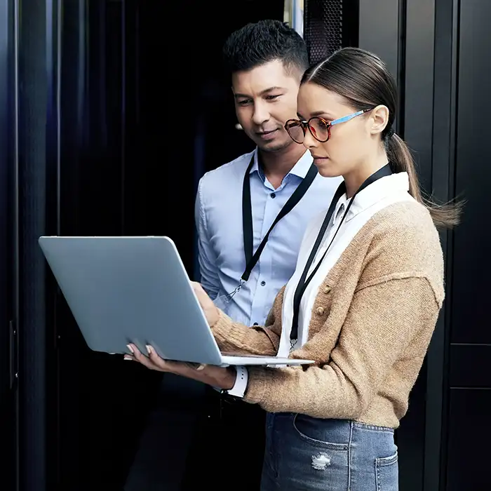 man and woman holding laptop in data center