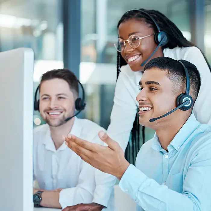group of workers with headsets on smiling while looking at computer