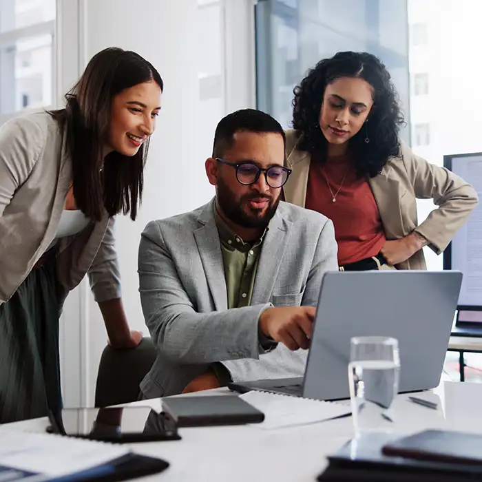group of office workers looking at laptop together
