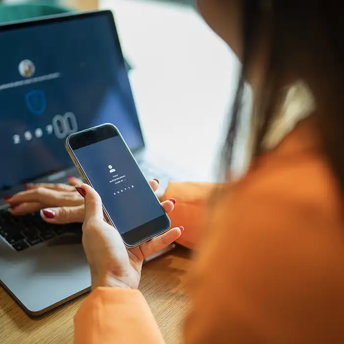 closeup of woman holding phone in front of laptop