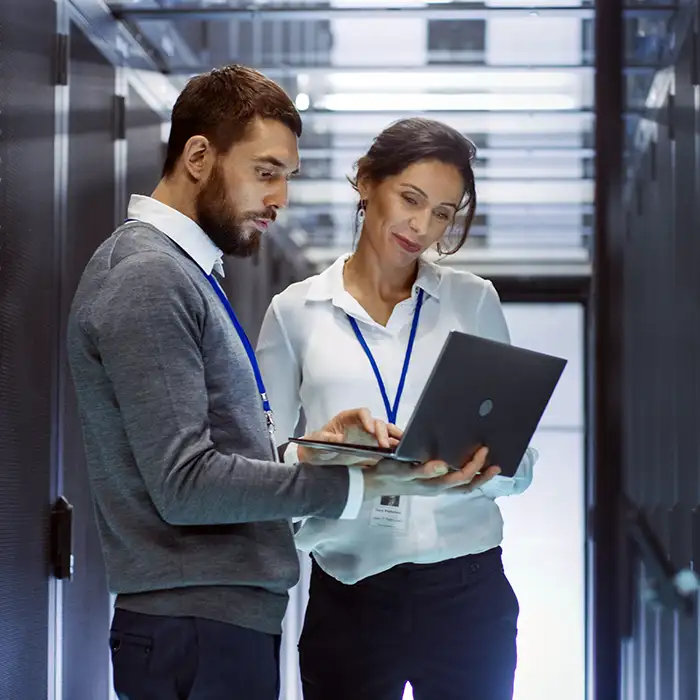 man and woman looking at laptop in data center