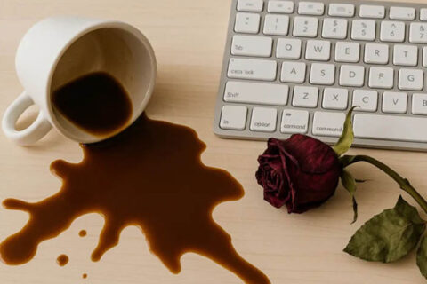 A spilled cup of coffee next to a computer keyboard